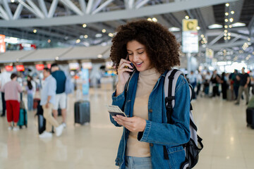 Fototapeta premium Latino woman talking on phone while walking through airport terminal. 