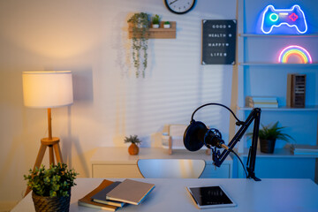 Modern cozy home office setup with microphone, notebooks, and plants on desk. 