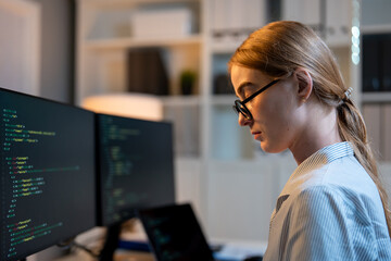 Caucasian young female software engineer working at night in the office. 
