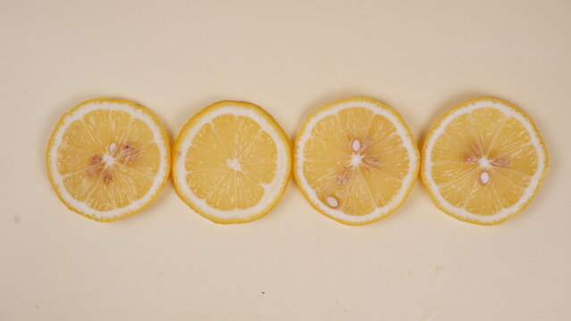 Four sliced lemon pieces arranged in a horizontal line, showcasing their internal details against a plain background.