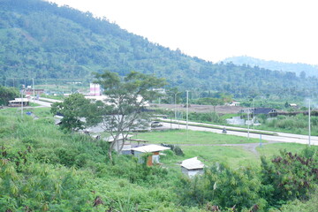 Serene Landscape with Rolling Hills, Lush Greenery, and Rural Roadside Scenery