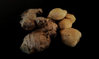 spices consisting of ginger, candlenut, pepper, and cinnamon on a black background.