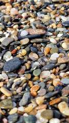 Close-up view of a diverse assortment of smooth pebbles and stones in various colors and sizes, creating a natural textured surface, ideal for backgrounds or artistic projects