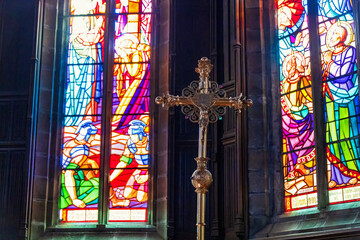Golden crucifix in a church with stained glass in the background