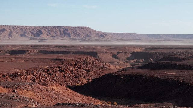 Side drone shot of morocco dry landscape with dust in rocky desert mountains