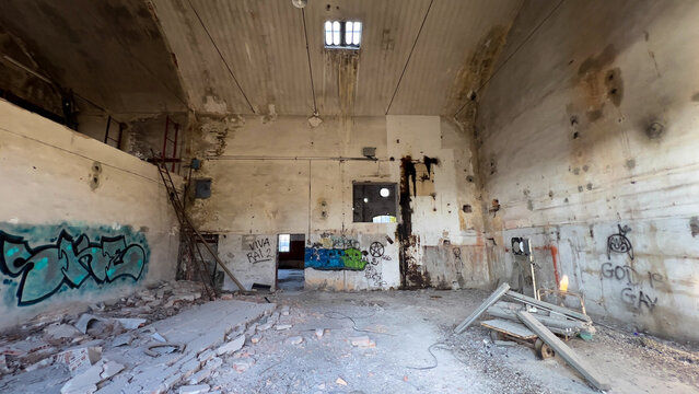 The wide view captures a massive abandoned industrial space with crumbling walls covered in vibrant street art