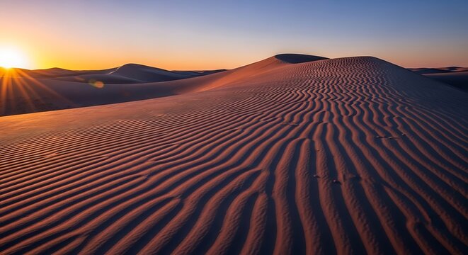 Golden sunset over undulating desert sand dunes and clear sky