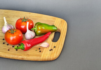 Composition of pepper, chili, garlic and tomato on a wooden surface.