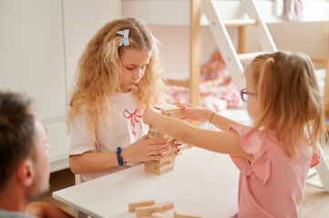 Children playing wooden block stacking game indoors