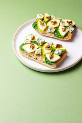 Bruschetta with spinach, honey, blue cheese, pear, and nuts. Healthy eating. Vegetarian food.
