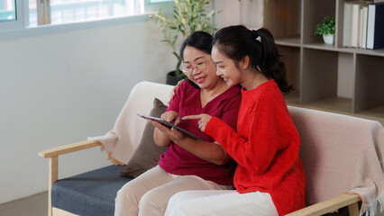 Shared joy. Mother and daughter exploring a tablet together in a cozy setting.
