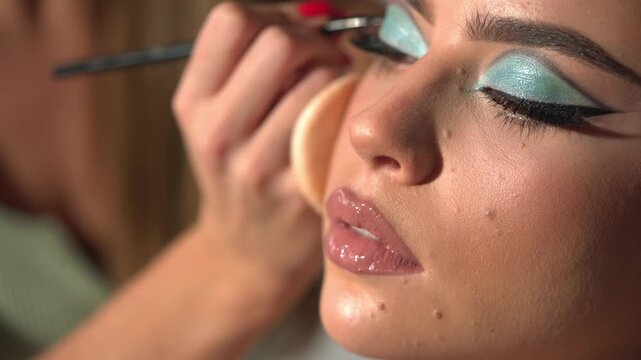 Professional makeup artist working with beautiful young woman. Close up makeup for young model. Makeup artist applying makeup. Professional Make-up artist doing glamour model make up. - Powered by Adobe