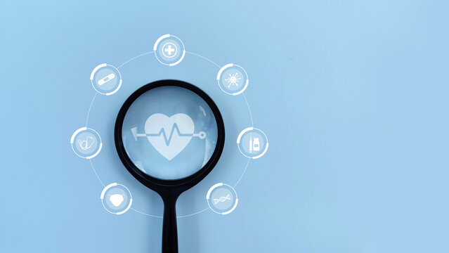 Magnifying glass focus on healthcare medical icon against blue background. Health insurance, medical technology concept.