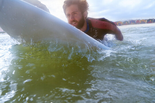 Athlete, man and paddle with surfboard in ocean for travel, fitness adventure and riding waves. Male person, board and surfing for extreme water sports, tropical holiday and practice technique at sea