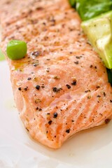 Grilled salmon close-up, garnished with green peas and herbs