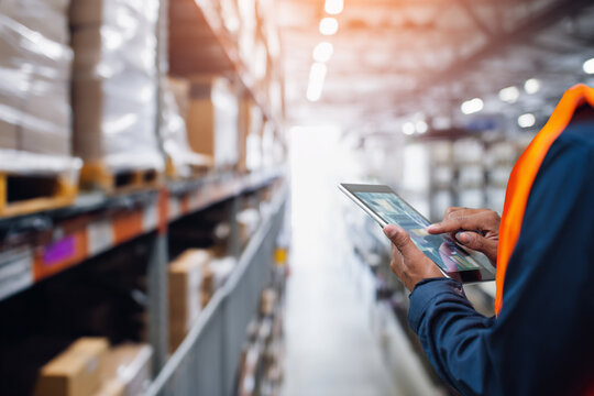 Efficient warehouse worker using tablet for inventory management in a modern distribution center, ensuring seamless logistics and supply chain optimization