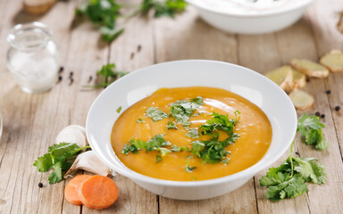 vegetable soup in bowl with herbs on wooden board