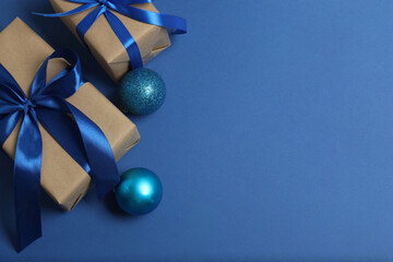 Top view of Christmas gifts with decorations on blue background

