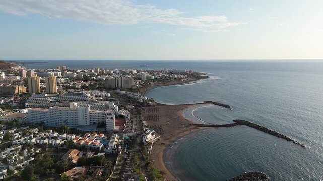 Aerial Drone POV of Playa de las Americas, which is an upscale resort on the southwest coast of Tenerife, the largest of Spain&rsquo;s Canary Islands. Ambient cinematic drone exploration.