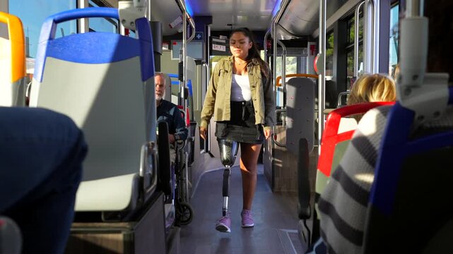 Determined amputee woman with prosthetic leg walking on bus