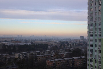 Cityscape view from high-rise building on cloudy autumn day, urban skyline with residential houses and overcast sky.
