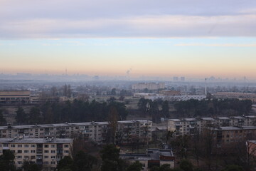 Cityscape view from high-rise building on cloudy autumn day, urban skyline with residential houses and overcast sky.