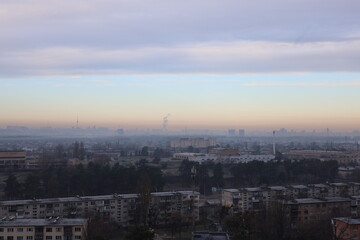 Cityscape view from high-rise building on cloudy autumn day, urban skyline with residential houses and overcast sky.