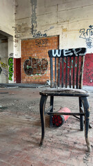 A solitary old wooden chair stands broken on the tiled floor inside a vast abandoned industrial space