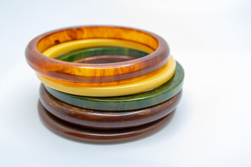 Close up studio shot of various color vintage bakelite bangle bracelets stacked on a white background, with copy space