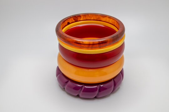 Close up studio shot of various color vintage bakelite bangle bracelets stacked on a white background, with copy space