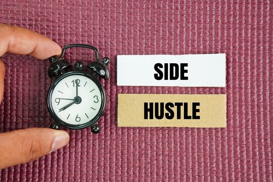 Alarm clock and paper with the word side hustle. an extra job outside of a main one to earn more money, build skills, or pursue a passion