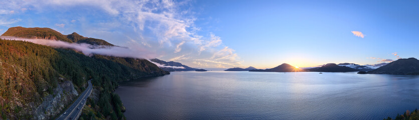 Fototapeta premium Panoramic Coastal Landscape With Sunset Over Howe Sound, BC, Mountains, And Serene Road