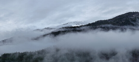 Misty Mountain Clouds Over Forested Ridge in British Columbia, Canada, Shrouded by Morning Fog
