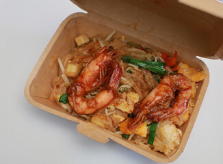 Pad Thai with fresh shrimp packed in a paper box on a white background