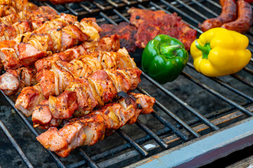 Grilled meat skewers and vegetables on barbecue at Christmas market, aromatic meats, peppers and sausages creating festive seasonal food atmosphere