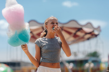 Girl eating cotton candy at amusement park on summer day