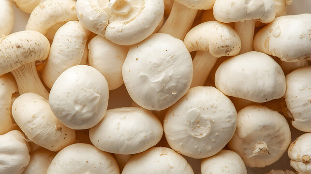 Close-up cluster of fresh white button mushrooms with smooth rounded caps, soft matte texture, and short stems, arranged naturally against a clean white background.