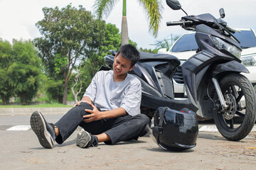 Motorcycle Rider Lies Injured on Asphalt After Collision With Car Helmet Nearby