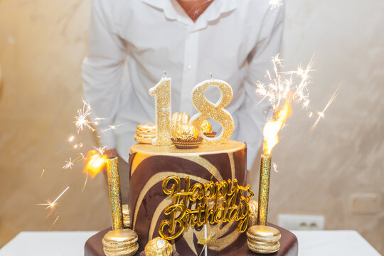 Luxurious 18th birthday cake adorned with gold candles, sparklers, and macarons