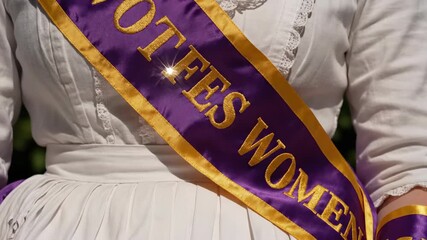 Women proudly wear sashes symbolizing their accomplishments during a lively festival. The sun shines brightly, and the atmosphere is filled with joy and celebration as they gather in unison.