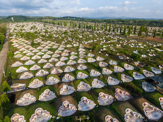 Aerial view of a large, traditional Chinese cemetery with hundreds of white tombs on green hills.