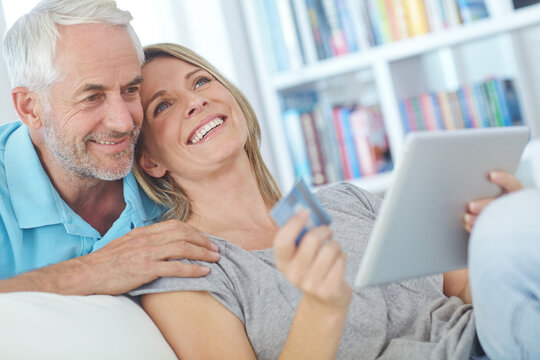 Mature couple, tablet and credit card on sofa with love, bonding and online shopping in home. Man, woman and technology in living room with purchase, payment and buying together for ecommerce