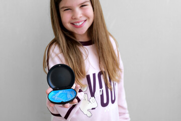 Teen girl presenting transparent aligners in small case, comfortable orthodontic solutions and daily dental care. Bright natural image ideal for clinics promoting aligners for kids and teens