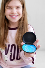 Smiling girl holding case with clear dental aligners, showing modern orthodontic care and teen dental hygiene. Close up lifestyle shot perfect for ads about aligners, dentistry, healthy teeth habits