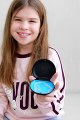 Teen girl presenting transparent aligners in small case, comfortable orthodontic solutions and daily dental care. Bright natural image ideal for clinics promoting aligners for kids and teens