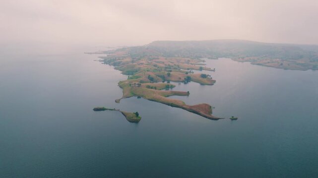 Aerial drone view of Banswara lakes and islands near Udaipur, Rajasthan, India, captured during a breathtaking sunrise, showcasing a cinematic blend of natural beauty with a boat moving across the wat