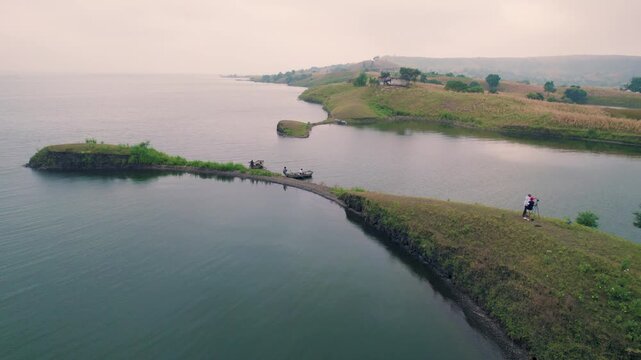 Aerial drone view of Banswara lakes and islands near Udaipur, Rajasthan, India, captured during a breathtaking sunrise, showcasing a cinematic blend of natural beauty with a boat moving across the wat