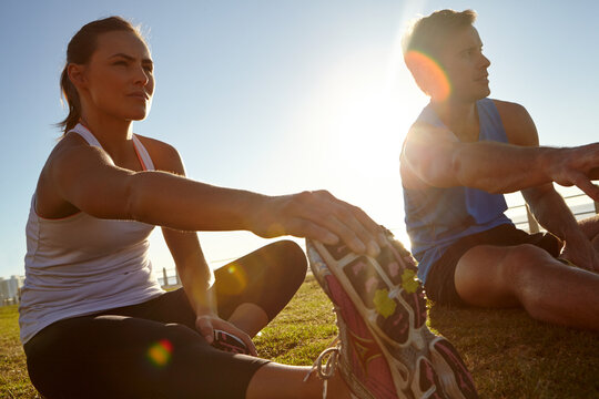 Stretching, promenade and people with fitness, training and challenge with lens flare. Outdoor, healthy woman and man on ground, workout and exercise with warm up, wellness and flexibility in Canada