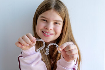 Teen girl showing transparent aligners in hands, comfortable teeth straightening options for children. Clean natural image ideal for orthodontic ads, dental care guides and family health content