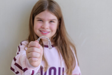Girl holding clear dental aligners in her hands, presenting modern orthodontic care for kids. Bright lifestyle shot suitable for dental clinics, aligner brands and healthy smile campaigns